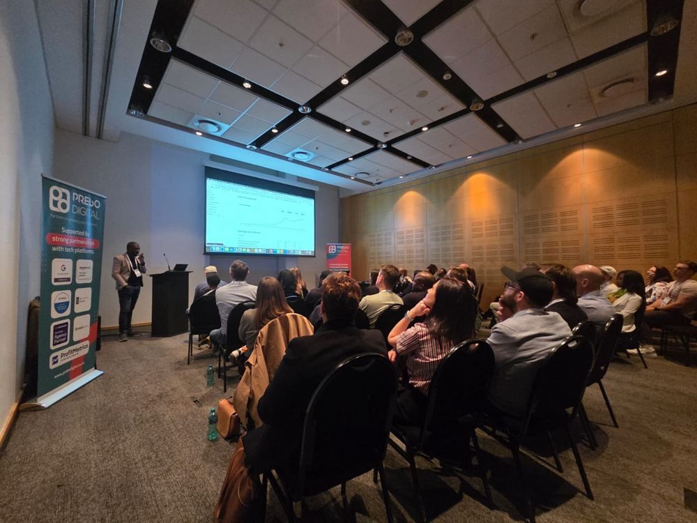 Presenting to a full room beside a Prebo Digital banner.